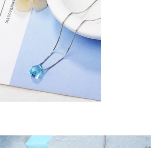Close-up of a blue waterdrop crystal pendant on a delicate silver chain necklace