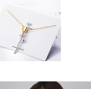 Macro detail of gold-plated rose pendant with silver leaves on a delicate chain
