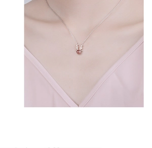 Detailed view of silver antler necklace with dark red bead on model neck
