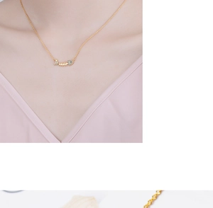 Close-up of a gold fishbone pendant necklace with blue crystals on a woman's collarbone