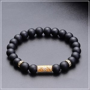Close-up of matte black natural stone beads with gold hollowed-out pavé zircon detail