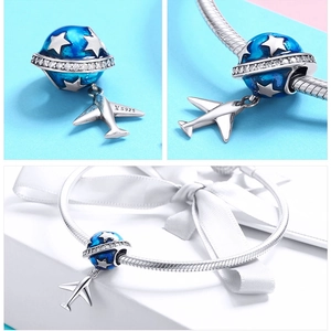Macro detail of S925 sterling silver globe and plane charm with blue enamel on a snake chain
