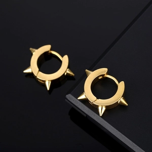 Golden stainless steel spike huggie earrings set on a reflective black background