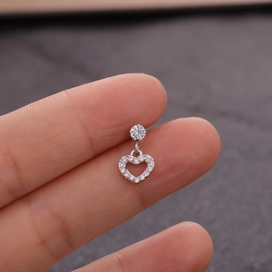 Macro detail of a silver heart pendant earring with zircon inlay shown on an ear