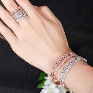 Detail view of layered rose gold and silver rings set with sparkling baguette zircon stones