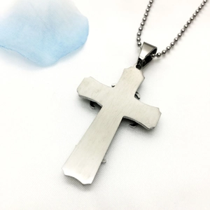Macro shot of three-layer stainless steel cross pendant with brushed metal texture