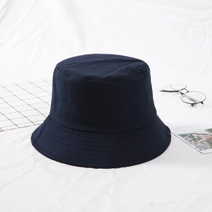 Detail of a navy blue canvas bucket hat on white fabric with modern minimalist props