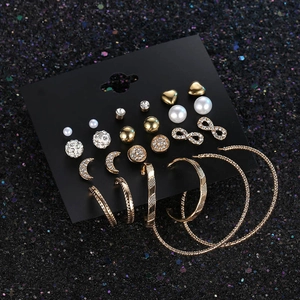 Set of 12 pairs of gold earrings with moon star studs and hoops on a black display card