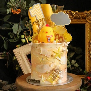 Detail of happy birthday acrylic cake topper with golden finish and cartoon chick ornament