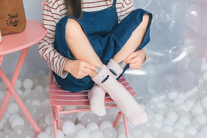 Detail of pink coral fleece socks featuring cute cartoon monster face and 3D horns