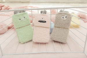 Three pairs of soft coral fleece socks with cute cartoon monster patterns in a metal basket