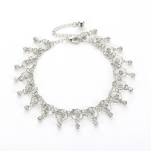 Close-up of silver anklet featuring clear rhinestone tassels and small bell pendant