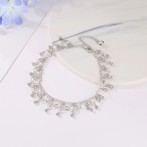 Elegant silver ankle bracelet with rhinestones and tassel charms on marble surface