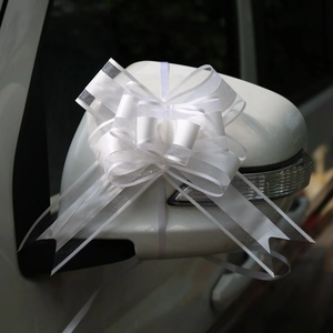 Primo piano di un fiocco di tulle bianco decorativo sullo specchietto di un'auto nuziale
