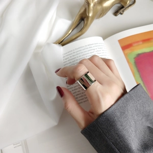 Close-up of a wide minimalist polished silver ring worn on a finger in a stylish setting