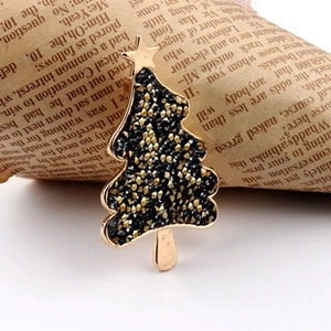 Detail of a gold Christmas tree brooch with black crystals on a vintage newspaper background