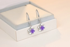Detailed close-up of purple gemstone flower earrings on a white jewelry display box