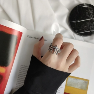 Macro detail of vintage 925 silver gothic cross ring on hand over marble and silk