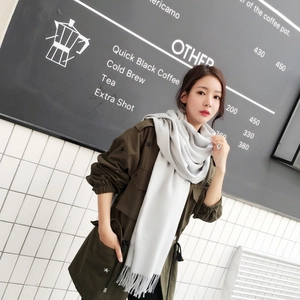 Detail of light grey cashmere-feel scarf featuring classic vertical fringe edges