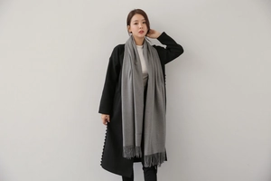 Detail of light gray cashmere scarf featuring delicate fringed edges and soft knit texture