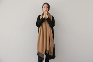 Classic camel tasseled scarf shown on model with black coat for autumn winter style
