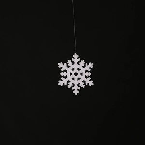 Close-up of sparkling white snowflake hanging decoration with glitter finish on black background