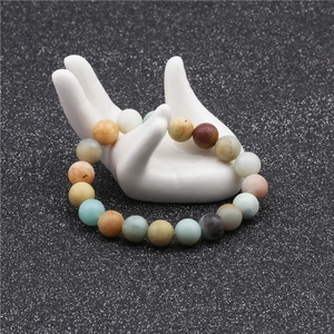 Macro shot of colorful 10mm natural stone beads on a white hand-shaped jewelry display stand
