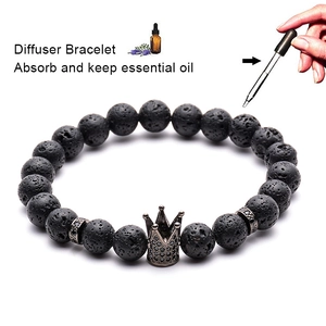 Detail of essential oil being applied to black lava stone diffuser bracelet with crown