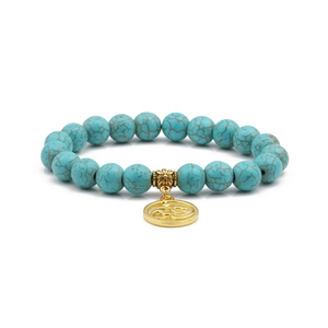 Detailed macro of 10mm turquoise beads and golden Om pendant on a beaded bracelet