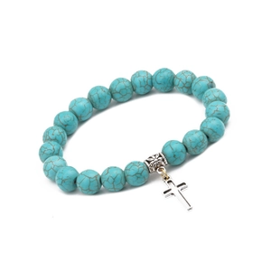 Detailed macro view of 10mm turquoise bead bracelet with a silver cross pendant