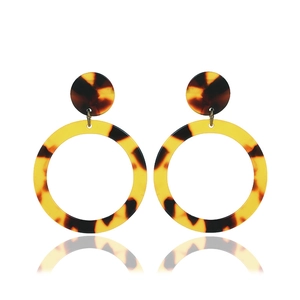 Macro shot of stylish C-shaped tortoiseshell leopard pattern acrylic earrings on white