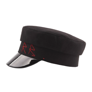 Black wool newsboy cap with patent leather brim and red letter embroidery detail