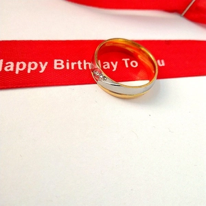 Detailed macro view of a two-tone steel ring with inlaid zircons on a white surface