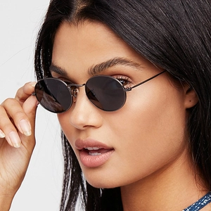 Retro oval sunglasses with black lenses and slim metal frame worn by a model