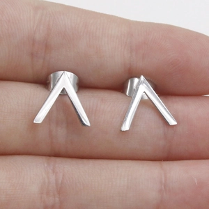 Detailed close-up of V-shaped stainless steel stud earrings with a polished silver finish
