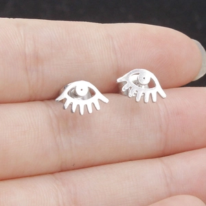 Detailed close-up of eye-shaped silver stainless steel stud earrings held by hand