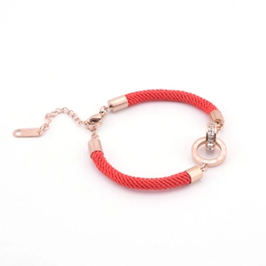 Detail of rose gold double rings with Roman numerals on a red woven bracelet