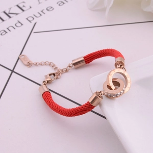Detail of rose gold double rings on red cord bracelet with Roman numerals and crystals