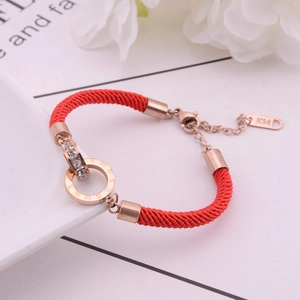 Close-up of rose gold double rings with crystals and Roman numerals on red rope bracelet