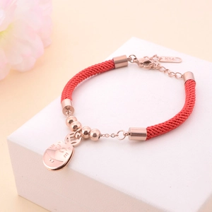 Minimalist 18K rose gold red string bracelet with lucky cat charm on a gift box