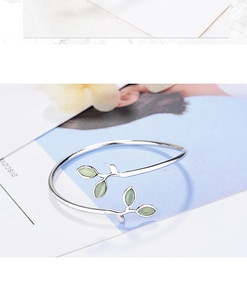 Close-up of adjustable silver leaf bracelet with soft green buds and cat eye stone details