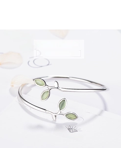 Detail of silver sprout leaf bangle with green cat eye stones on a branded card