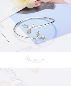 Macro shot of silver sprout cuff bracelet featuring cat eye stone green leaves detail