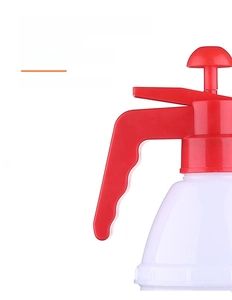 Macro detail of ergonomic red handle and power-saving thumb switch on a pressure sprayer
