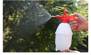 Macro shot of manual pressure sprayer showing fine misting effect for garden plants