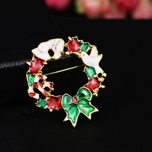 Detailed view of Christmas wreath brooch featuring enamel Santa hat and candy cane motifs