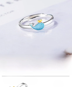 Detailed view of an adjustable silver whale ring with blue enamel and gold water droplet