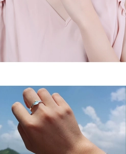 Detail of whale ring with blue fish charm and gold crown on model finger outdoors