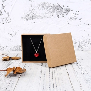 Detail of vintage kraft paper jewelry box with black lining and heart necklace inside