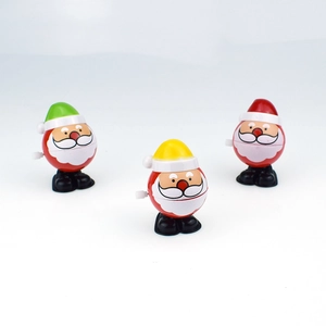 Close-up of three wind-up Santa toys with red, yellow, and green hats on white background